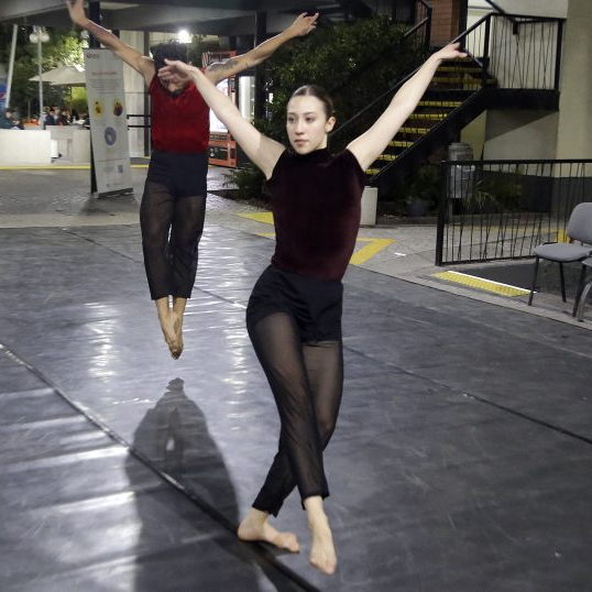 Bailarina con los brazos extendidos y bailarín de fondo